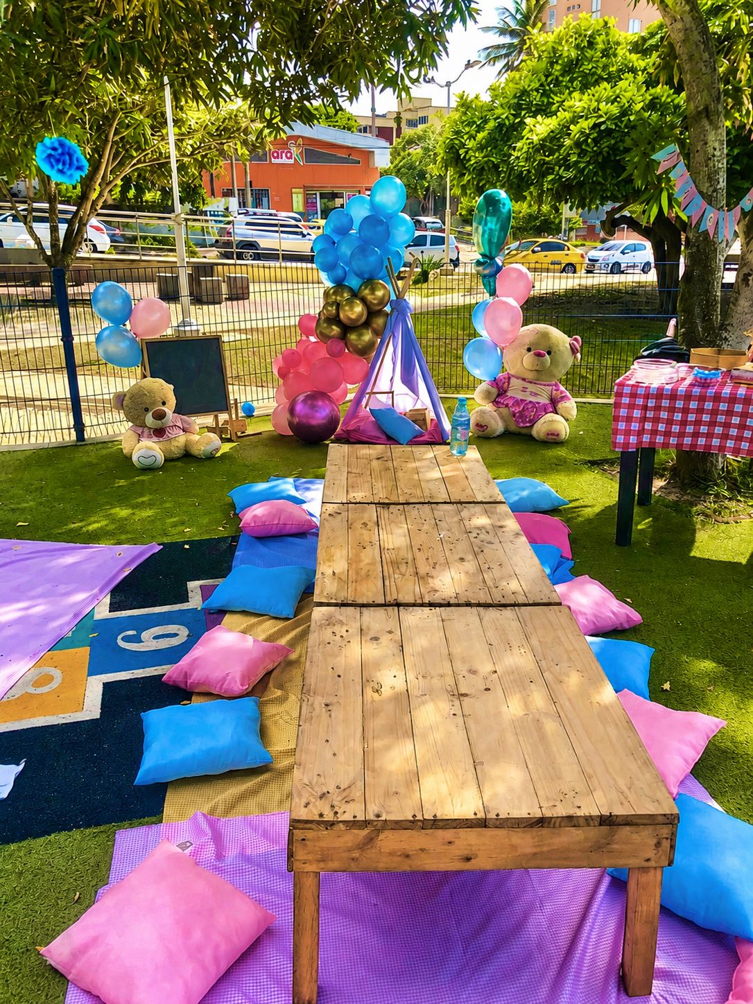 Montaje infantil al aire libre con mesa, globos y cojines